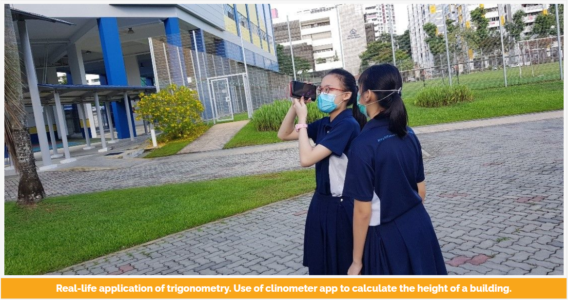 Two masked schoolgirls in navy uniforms use a phone as a clinometer outdoors to measure a building's height.